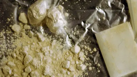 Getty Images Rocks of powdered cocaine - or crack - as well as little white bags of the drug arranged on a flat surface