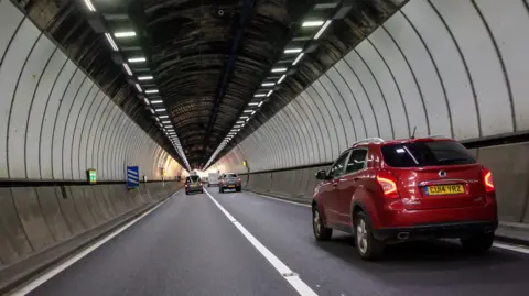 Huw Fairclough/Getty Images One of the two Brynglas Tunnels in Newport, with cars in both carriageways. A red car is closest to the camera on the right hand side.
