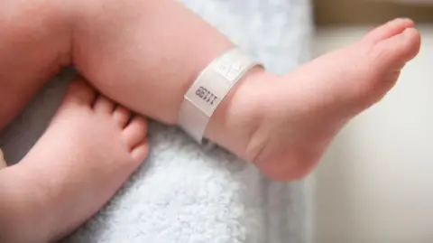 A baby's feet with a hospital tag on a white towel 