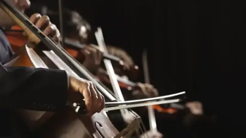 A close up image of someone playing the cello.