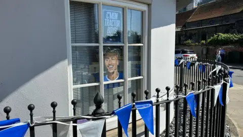 Ben Parker/BBC A railing outside a building. There is blue and white bunting on the railing, and in the window are posters supporting Ipswich Town.