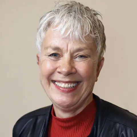 Dumfries and Galloway Council A woman with short grey hair in a black leather jacket with a red jumper underneath