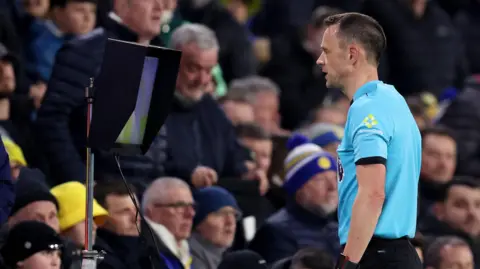 Referee looks at VAR monitor during Premier League match