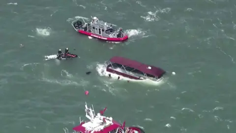 Aerial images of a sinking boat in San Francisco Bay surrounded by emergency response vessels. 
