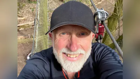 Family handout A selfie of David Darke, a 66-year-old white man wearing a sports top and a black cap. He appears to be at an outdoor activity centre.