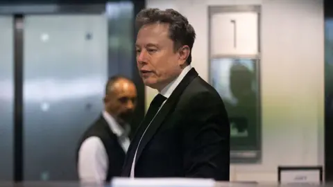 Elon Musk wearing a black suit arrives to court for his lawsuit against OpenAI in Oakland, California.