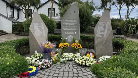 The memorial, which is three standing stones in a circle inscribed with the names of those killed.