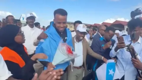 Referee Omar Artan returning to Somalia and being given flowers