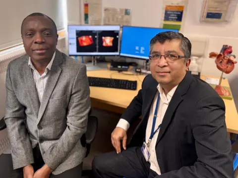 Two surgeons are sat side by side with images of Vanellope's heart CT scan on a computer behind them
