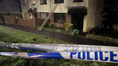 A house with a  police barrier across it 