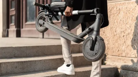 Getty Images Man holding folded e-scooter