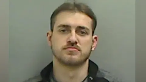 Cleveland Police A mugshot of Dale Hamilton. He is looking into the camera with a slight frown. He has dark, short hair and a beard. He is wearing a black and grey zippy top.