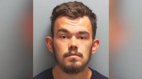 Custody image of Richard Hawes - bearded and wearing a dark-coloured top