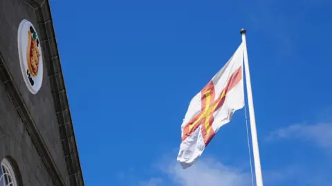 BBC The front of the States of Guernsey building with a flag to the right.