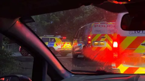 two police vans and a police car photographed from inside a car