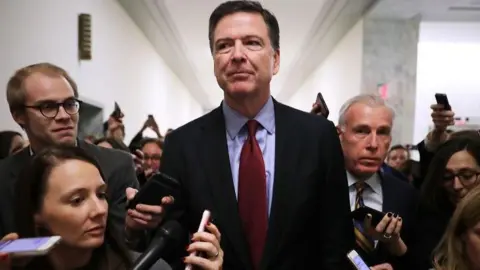 Getty Images Comey is questioned by reporters outside of a congressional committee hearing in 2018