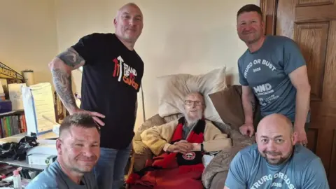 Heather Haigh-Prothero Four men with Chris Haigh-Prothero at the centre in a chair. 