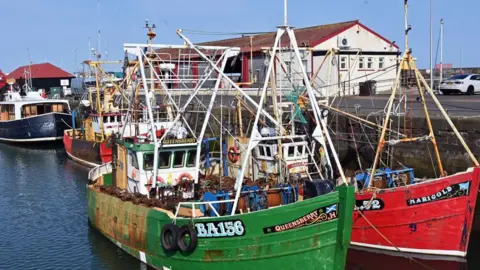 Getty Images Two fishing boats at Abroath Harbour - one is green and one is red. 