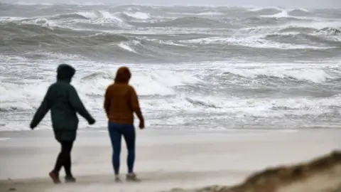 Two women walk on a beach 
