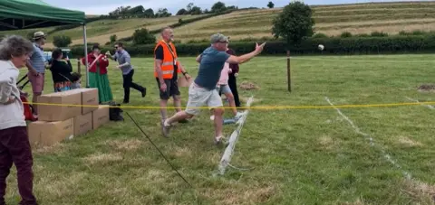 Field with people lined up ready to throw Dorset Knob biscuits