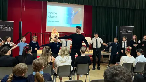 Reece Clarke teaching students ballet in a school hall