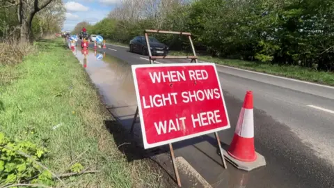 Traffic lights on a partially flooded rural road.