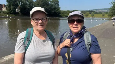 Sadie has a grey t-shirt and grey cap, while Anne has a blue t-shirt, scarf and light grey coloured cap.