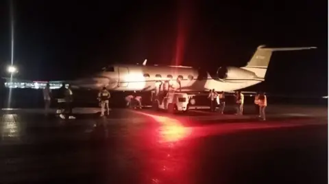 Airport officials inspecting a stalled aircraft on a runaway 