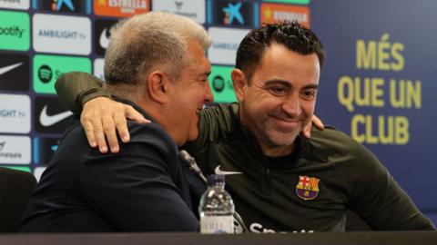 Barcelona president Joan Laporta (L) and coach Xavi react during a media conference