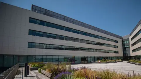 Getty Images The grey-fronted and tinted-windowed Tameside Council buildings in the Tameside One development with a light grey piazza in front, bordered by flowers and grasses