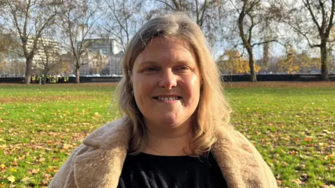 Councillor Grace Williams, leader of Waltham Forest, looking at the camera. She is standing in Victoria Tower Gardens in Westminster