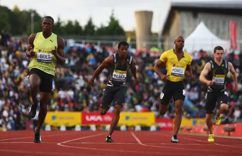 Getty Images Usain Bolt sails through the finish line at Crystal Palace track with competitors alongside him and crowds in the background.