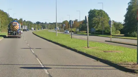 Google dual carriageway road called Bletcham Way in Bletchley, Milton Keynes showing a distant HGV and car and central reservation poles