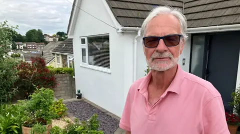 Man standing in the front garden of a house 