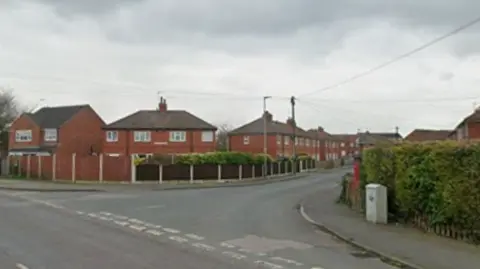 A street with houses lined on either and a van parked on the road side. 