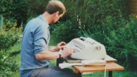 A man typing in a garden