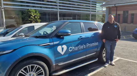 BBC/Julia Abbott Martin Cosser with his car branded with Charlie's Promise in Guildford