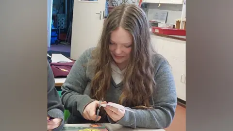 Gatton Park A teenage girl sat at a table cutting pieces of paper.