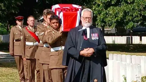 Crown Copyright A coffin covered in a British flag being carried by soldiers.