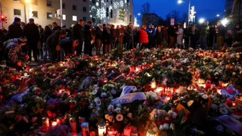 Reuters Plush toys, candles and floral tributes lie near the site where a car drove into a crowd at a Magdeburg Christmas market in Magdeburg, Germany December 21, 2024