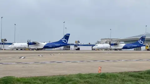 Two Blue Islands planes at Jersey Airport with the terminal building behind.