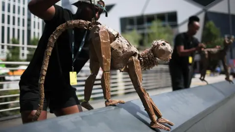 EPA Puppeteers operate puppet animals during a preview for 'The Herds' - A wooden monkey puppet is walking on a wall
