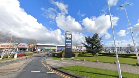 Google view of the entrance to Kingswood Retail Park in Hull. You can see the road leading to the shops off a roundabout and a 'Kingswood Retail Park' sign.