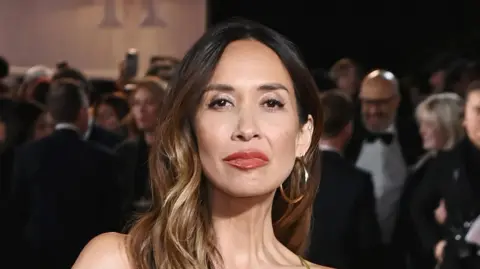 Getty Images Myleene Klass looks directly at the camera, wearing large gold earrings and has light brown wavy hair