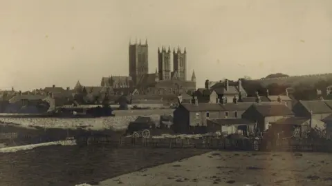 Lincolnshire Archives An archive photo of Lincoln Cathedral in 1904 at the top of the city,
surrounded by rural buildings, walls and cottages.