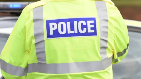 Police man from behind in hi-vis jacket