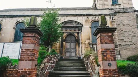 All Saints Church, Worcester The front of a church building, showing steps going up to a wooden door.