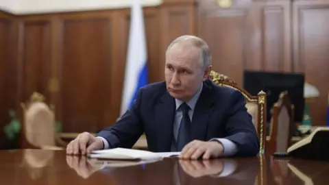 EPA/Russian presidential office Vladimir Putin sitting at a desk