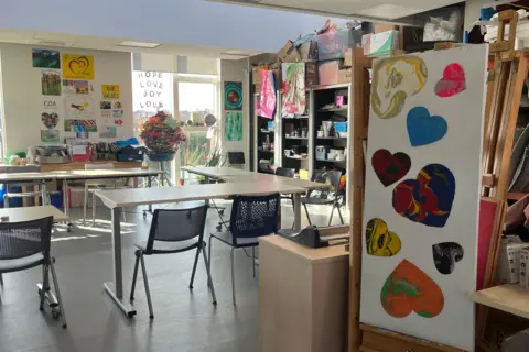 Greenwood Centre classrooms shows homemade hearts on display in a classroom with desks and chairs and a bright window letting light it