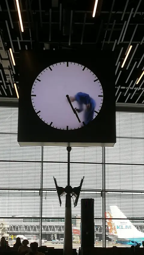 Bridget Perkin A person cleans the clock at Schiphol airport